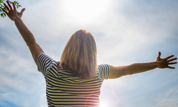 Female with arms outstretched looking up at the sky
