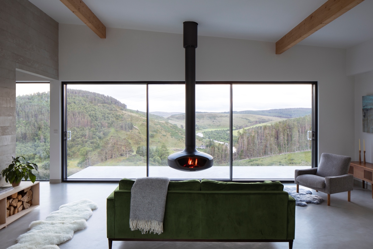 Indoor space with sofa looking at wood burner with window screen behind